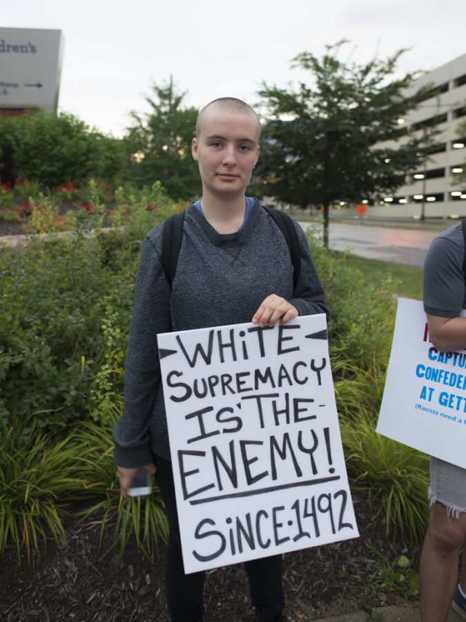 A white protestor at an anti-racism protest holds her sign.