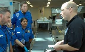 Two TSA workers standing together in an airport security checkpoint.