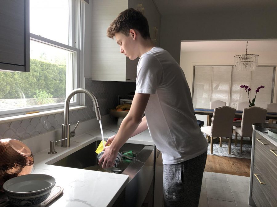 Sophomore Denis Sadrijaj washes off a bowl in his house. Sadrijaj helped care for his father who battled the coronavirus for many weeks. 