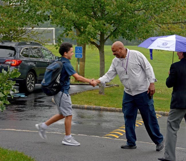 The late Masters security guard Panton Adams greets students outside the Middle School in the pouring rain on the first day of school in 2017. Adams, notorious for knowing every students name on campus, passed away from COVID-19 on Monday, Feb. 1.  