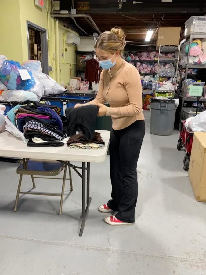Lily Schwarcz '22 sorts through clothes at Sharing Shelf, a clothing bank located in Port Chester.
