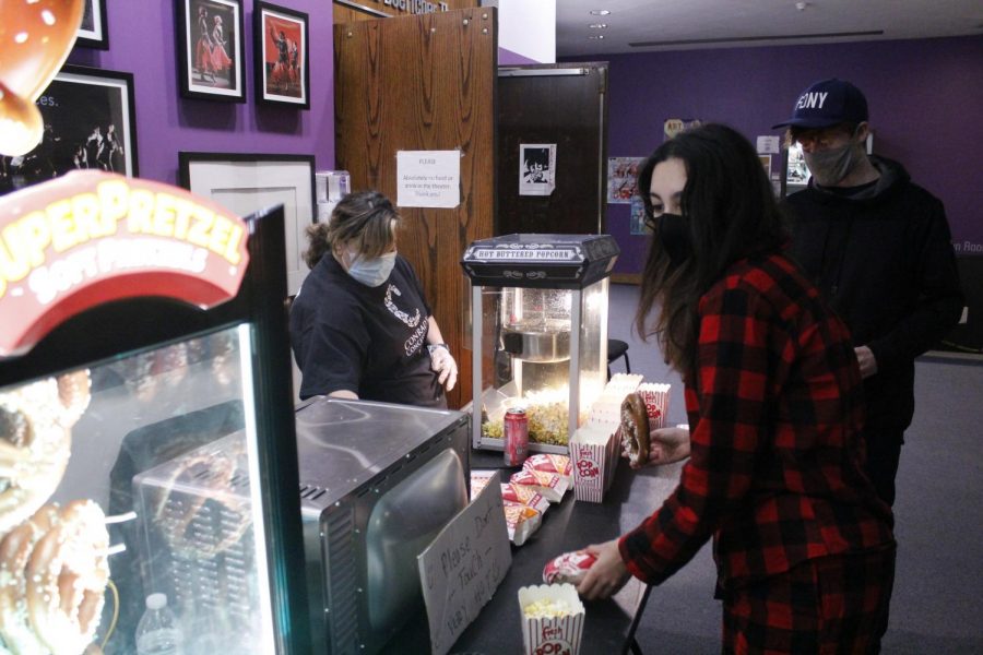 Senior Daniela Batista (left) and Rowan Walter (right) peruse the snack selection before movie night starts. Jeff Carnevale, dean of students, organized the logistics for the pretzel and popcorn machines, which were brought in from an outside vendor. Shelly Kaye, Class of 2022 dean, bought soda and candy for the movie night as well.