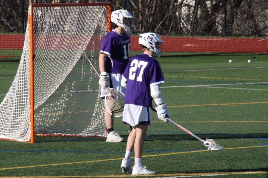 #18 Goalkeeper Nate Meyer ’22 and #27 defender Matt Sanzenbacher ’24 stand side-by-side as they wait for the second half of their April 8 home game against Wooster. The boys ended with a disappointing loss of 7-14, however, they hope to bounce back throughout the season.