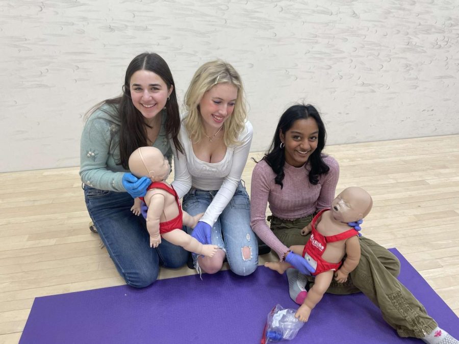 Students Grace Maher, Karina Mangru and Taylor Marlowe learning how to do CPR on an infant