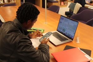 A student studies in the library by using practice problems.
