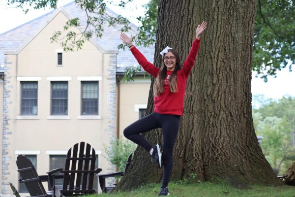 A student stands on the quad in the tree pose. 