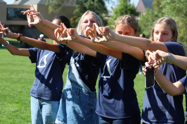 Junior girls holding up Delta symbols to the competition across the field.