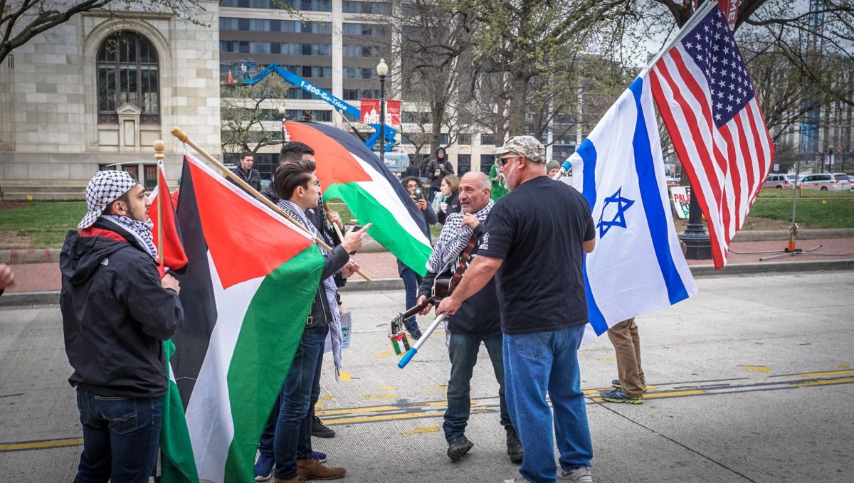 Protesters holding Israel flags and Palestine flags engage in discourse  during protest. Discourse throughout the nation has taken many forms including conversation just like these on city streets.