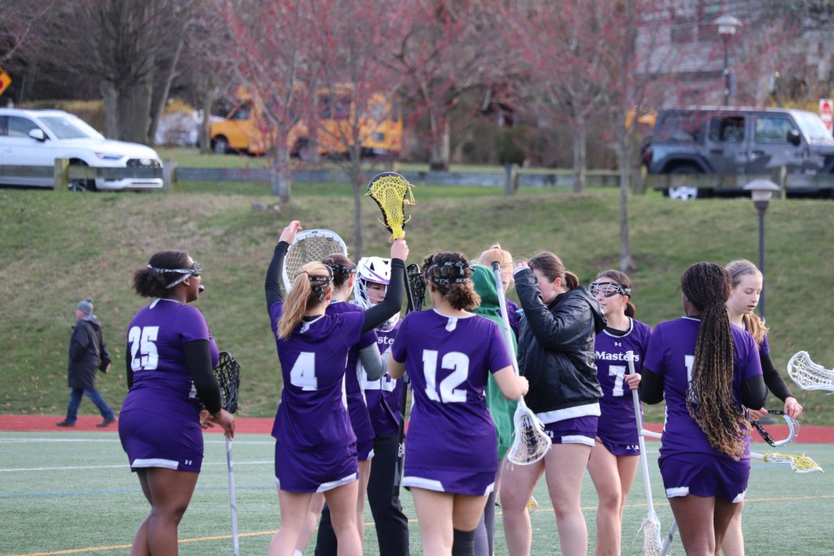 The varsity girls lacrosse team celebrates together on the field.