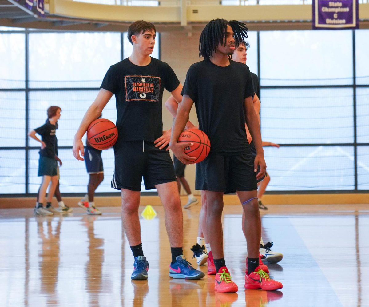 Luc Brongniart '26, left, and Omari Levy '26, right, prepare to execute a drill during boys basketball tryouts. Both Brongniart and Levy will join the team for this upcoming season.  