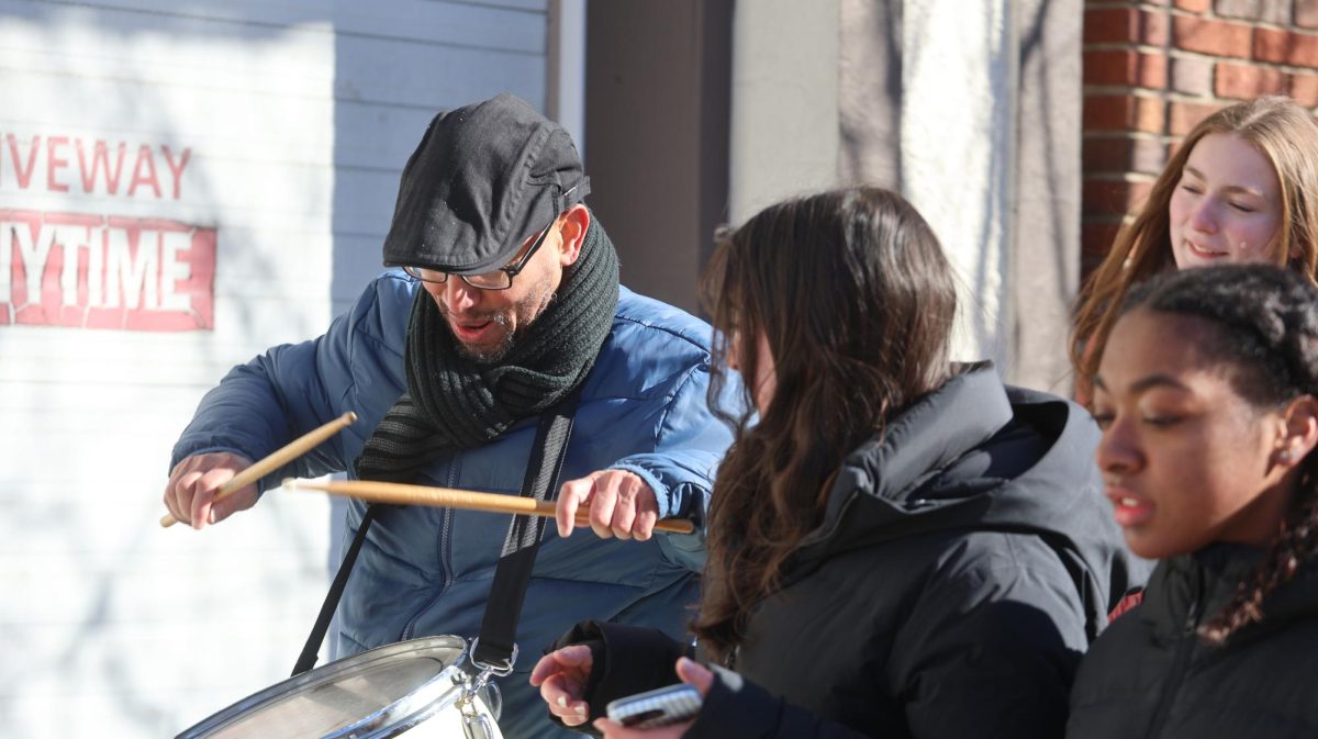 Upper School Spanish Teacher Roberto Mercedes and Beatrice Steiner '26 find a drum rhythm for a protest chant. Willow Lovett '26 and Waverly Beckwith '29 walk alongside them.