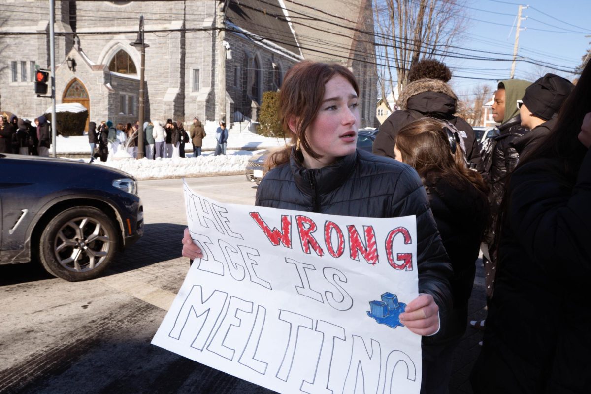 Bella Henriquez '26 holds a sign that reads "THE WRONG ICE IS MELTING" as she walks with fellow Masters students, faculty and administration through downtown Dobbs Ferry.