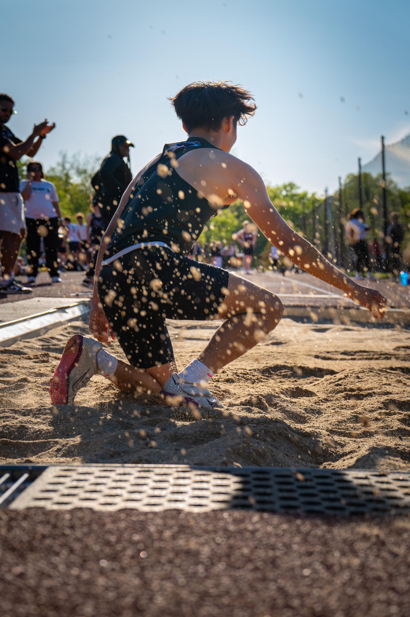 AJ Nguyen comes crashing down into the sandpit during the Fairfield Athletics Association (FAA) championship meet. Though he initially joined the team to sharpen his basketball skills, Nguyen discovered his talent in track and field.