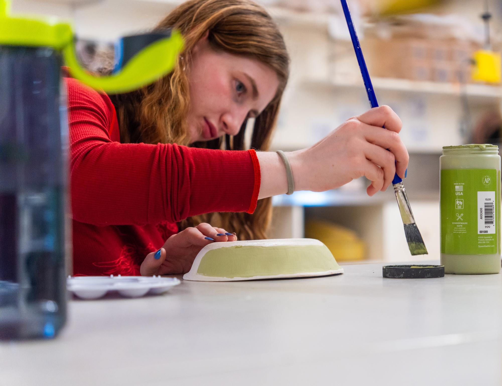Lorelei Gary '26 paints a bowl with glaze during the Empty Bowls at Masters glaze night event. Students and faculty were invited to the ceramics studio to paint the pottery that was made in a previous event. A sale of the bowls will be hosted on May 1 to raise money for Feeding Westchester.