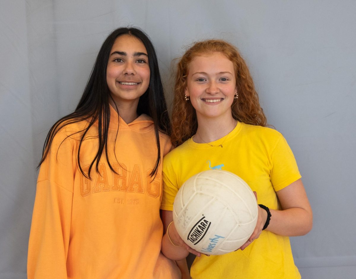 Leela Gibson '29 and Marcelle Clunie '29 smile and pose with a volleyball. The two girls manage the boys volleyball team this season.